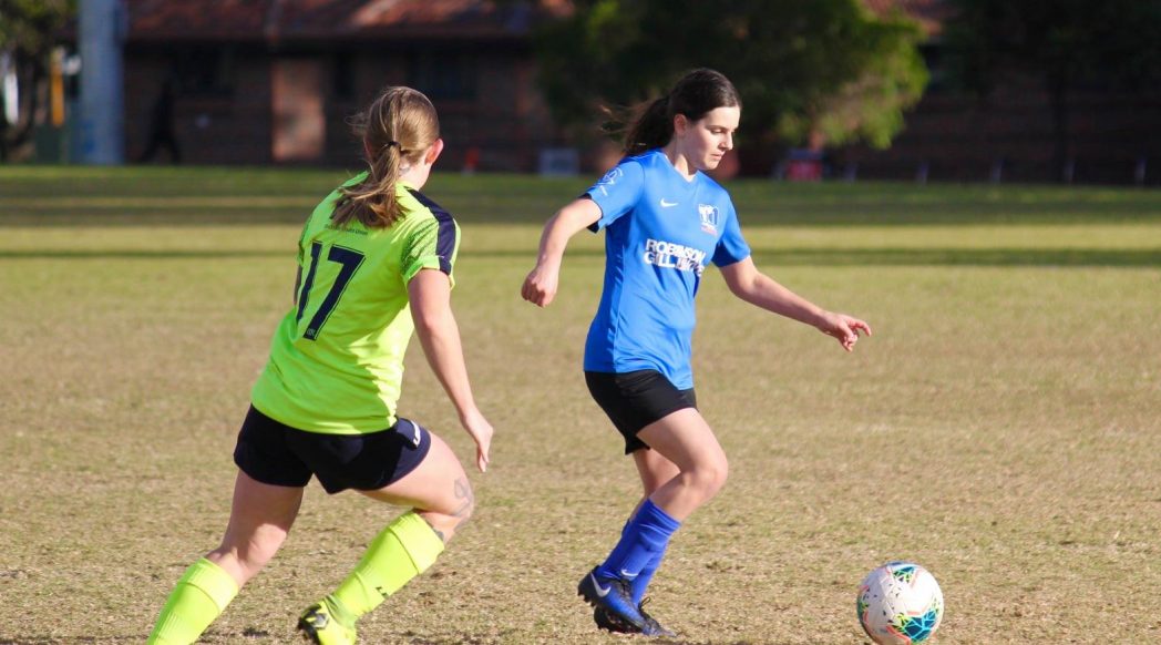 Cicc with the ball at her feet, and an opposition player approaching from the left side of the photo